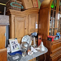 Houten meubels en huishoudartikelen op display, waaronder kasten, klok en diverse spullen