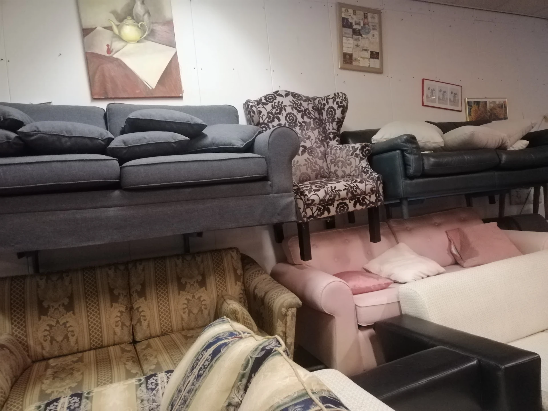 Uitgestalde meubels in de kringloopwinkel: banken, fauteuils en stoelen in verschillende kleuren en stijlen