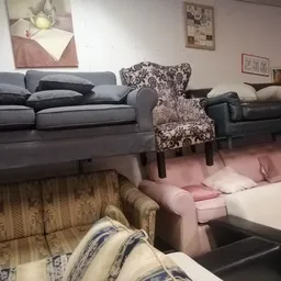 Uitgestalde meubels in de kringloopwinkel: banken, fauteuils en stoelen in verschillende kleuren en stijlen