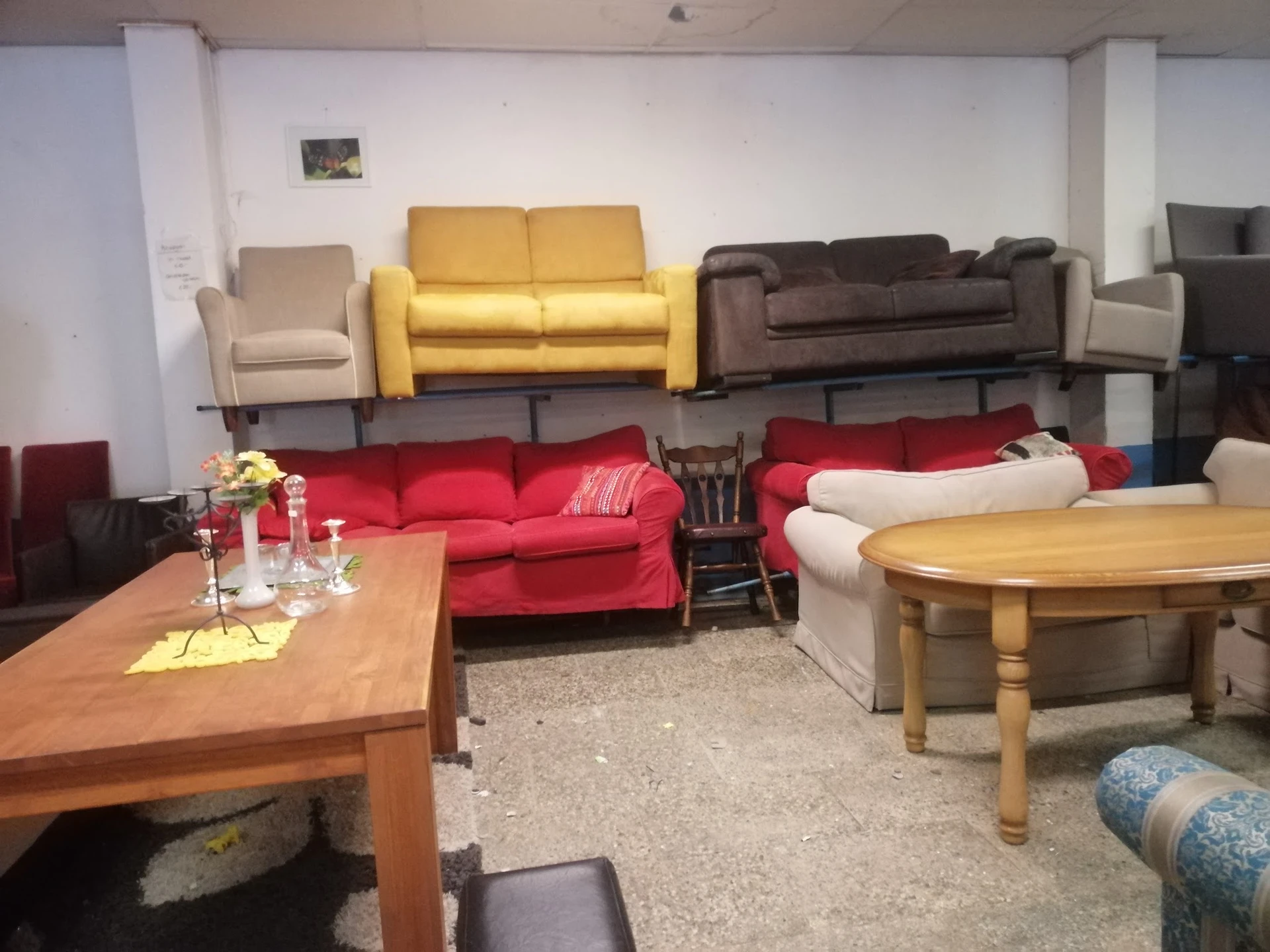 Showroom met diverse zitmeubels: gele, rode, bruine en beige banken en fauteuils, houten tafels op zandkleurig tapijt