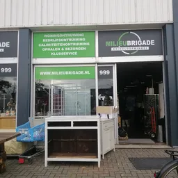 Winkelgevel met groene en zwarte belettering, vitrine met dameskleding, ingang met witte deur
