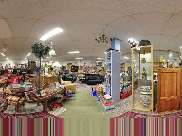 Winkelvloer van kringloopwinkel met meubels, boeken, decoratie en vitrines vol spullen