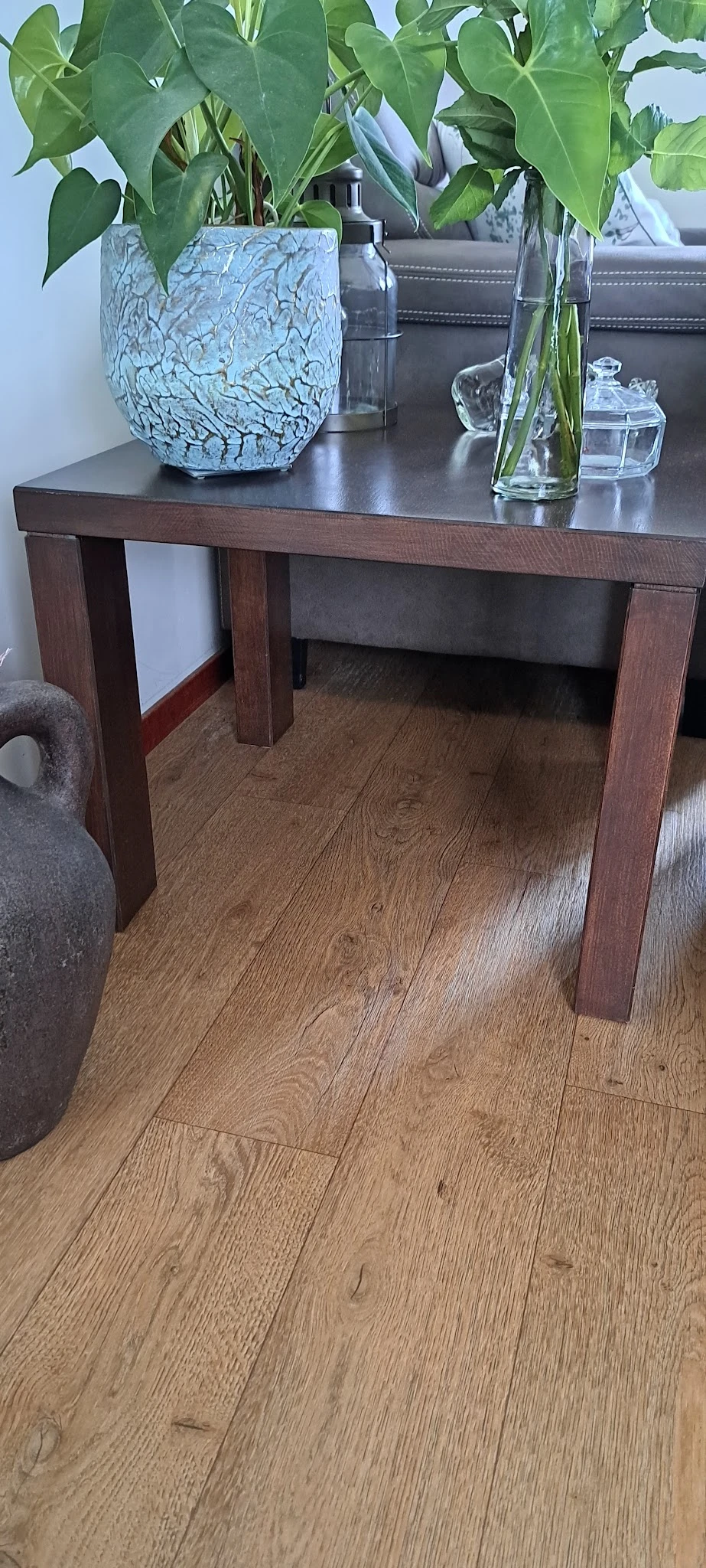 Onderaanzicht van een houten tafel met donkerbruin blad en poten, op houten vloer