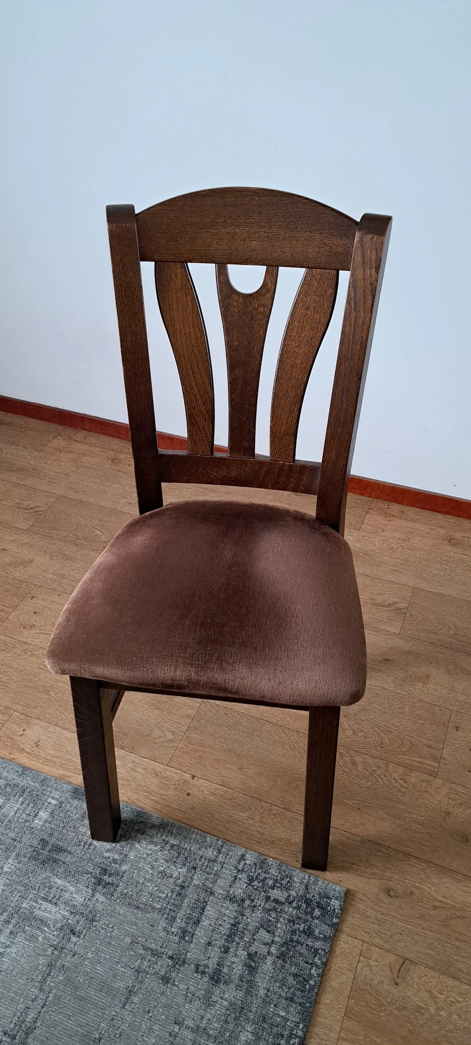 Houten stoel met bruine bekleding, gezien vanaf bovenkant tegen laminaat vloer