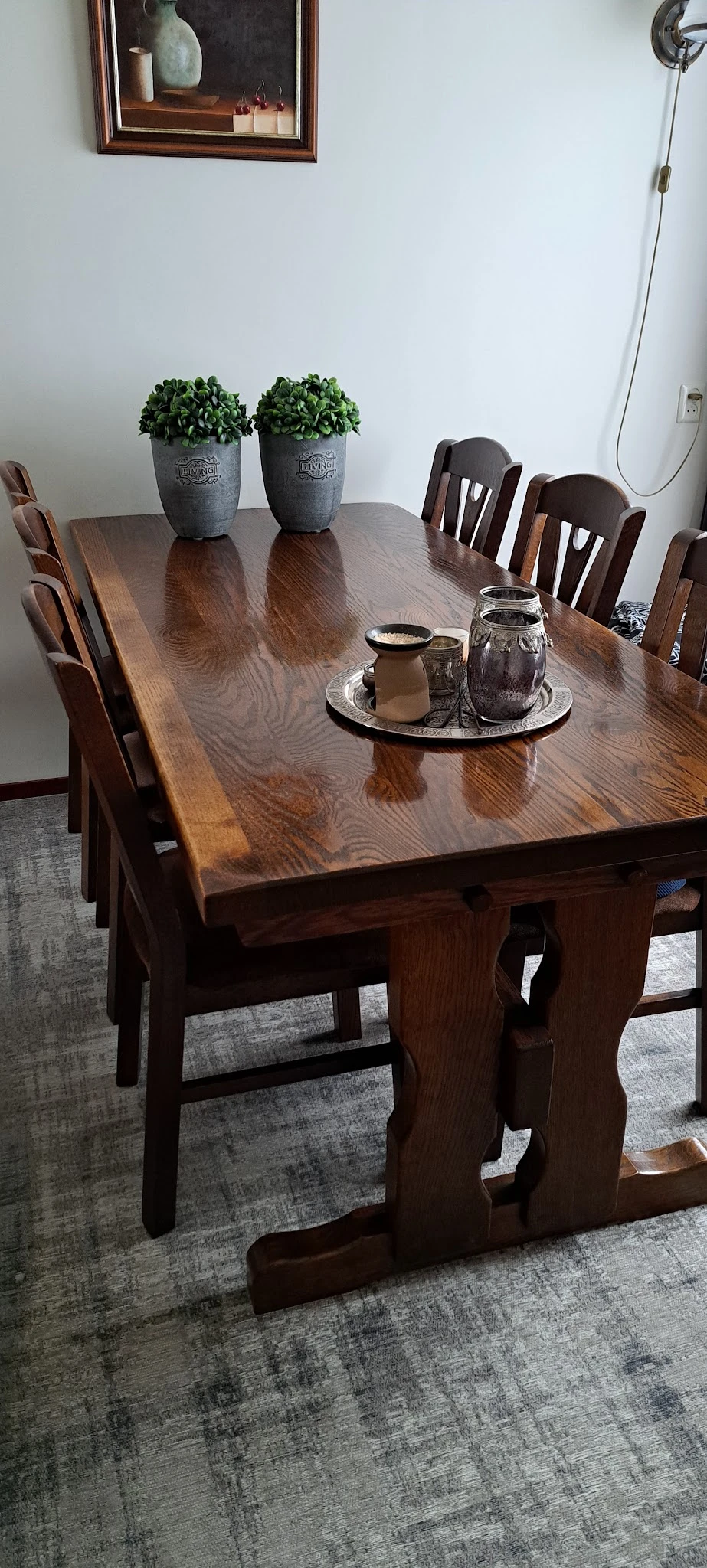 Donkerbruin houten eettafel met stoelen en een zwart dienblad met glazen potjes erop