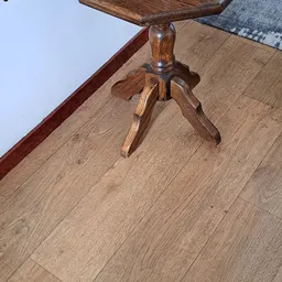Houten staande lamp met drievoetige voet op houten vloer