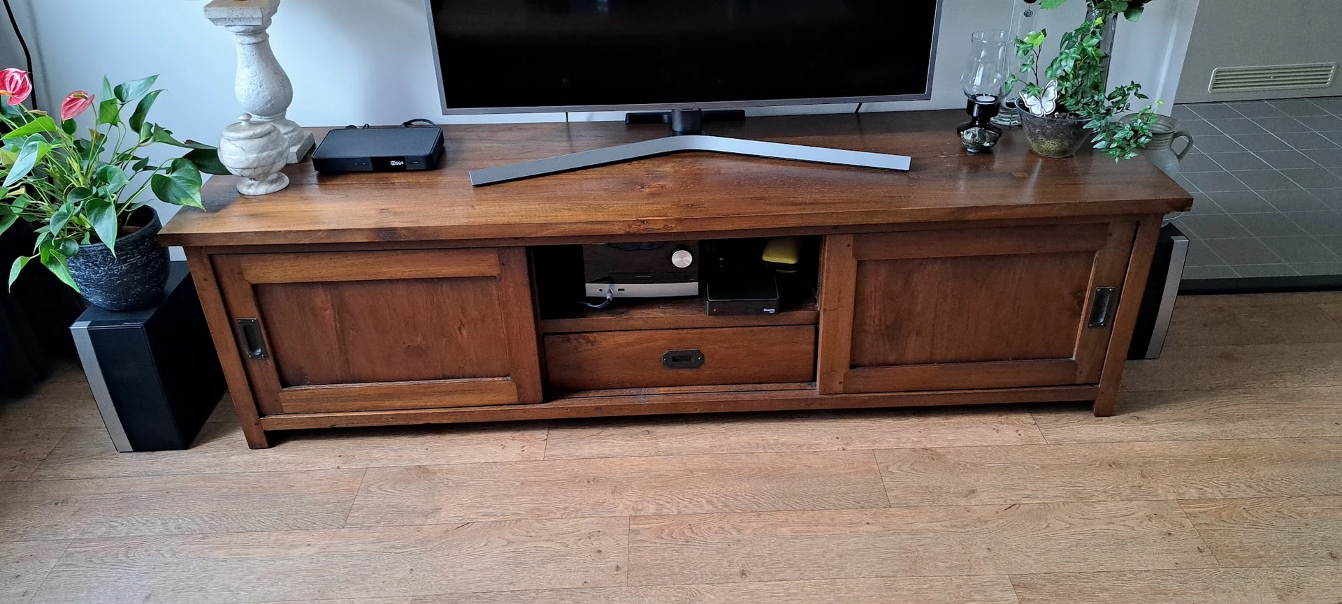 Houten tv-meubel met open vak en gesloten kasten, op houten vloer met televisie erop