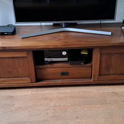 Houten tv-meubel met open vak en gesloten kasten, op houten vloer met televisie erop