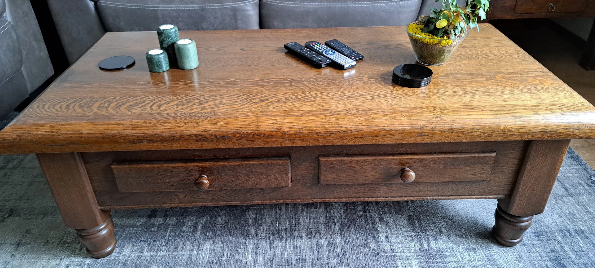 Houten salontafel met twee laden en houten knoppen, op een grijze rug.