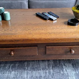 Houten salontafel met twee laden en houten knoppen, op een grijze rug.