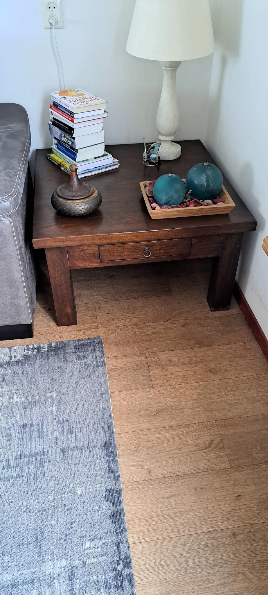 Donkerbruin houten sidetable met lade en open onderblad, op houten vloer
