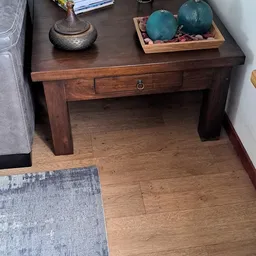 Donkerbruin houten sidetable met lade en open onderblad, op houten vloer