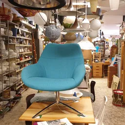 Turquoise moderne fauteuil op wieltjes in een kringloopwinkel