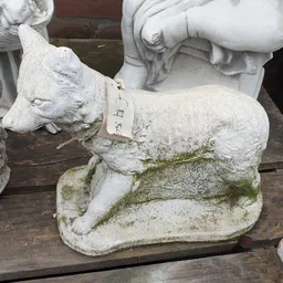 Stenen beeldje van een liggende dier met groene aanslag, close-up van tuinbeeldhouwwerk
