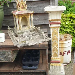 Diverse tweedehands decoratieartikelen en religieuze beelden op een tafel buiten de winkel