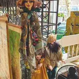 Kinderen in een kringloopwinkel tussen rekken met kleding en spullen, zonnig binneninterieur zichtbaar