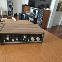 Vintage audioversterker met houten frontpaneel en zwarte bedieningselementen op houten tafel