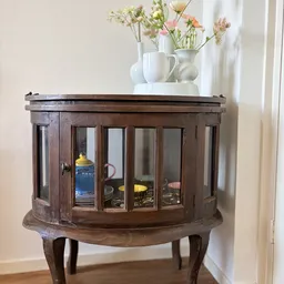 Houten vitrinekast met glazen deuren en glas-in-lood patronen, gevuld met serviesgoed en decoratieve items