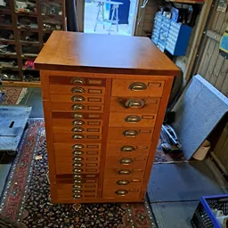 Houten vintage apothecerskast met talrijke kleine laden en koperen handgrepen