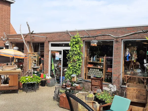 Voorkant kringloopwinkel met bakstenen gevel, etalageruiten en houten decoratieve elementen