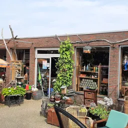Voorkant kringloopwinkel met bakstenen gevel, etalageruiten en houten decoratieve elementen