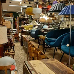 Winkelvloer met diverse meubels: houten stoelen, blauwe fauteuils, lampen en tafels uitgestald