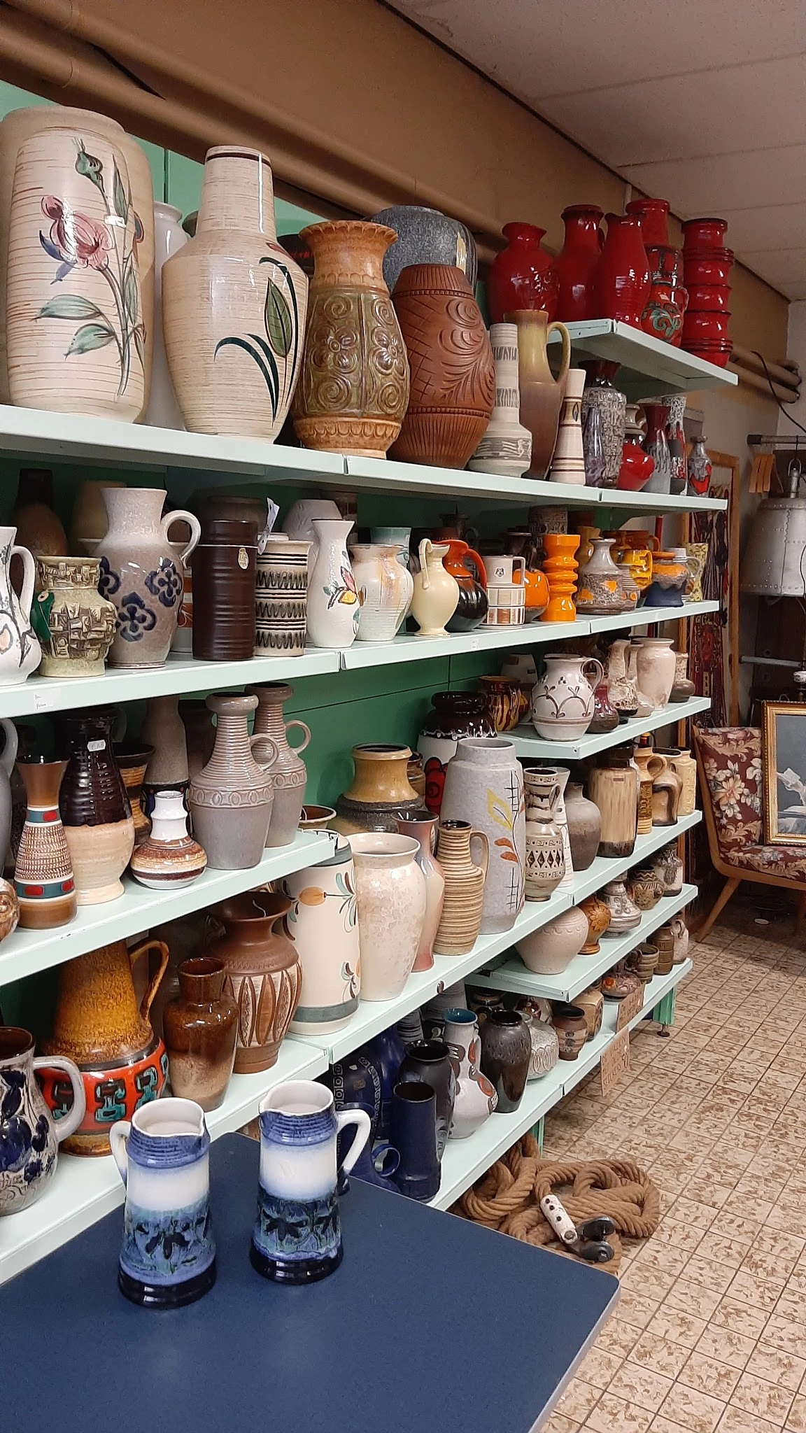 Metalen stellingen met diverse aardewerk, kannen, kruiken en decoratieve keramiek uit verschillende periodes