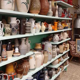 Metalen stellingen met diverse aardewerk, kannen, kruiken en decoratieve keramiek uit verschillende periodes