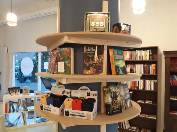 Winkelinterieur met houten displaykasten vol boeken, media en klein huishoudelijk spul