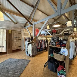 Ruim kringloopwinkelinterieur met kledingrekken, hangkleding, planken met spullen en winkelbus