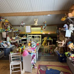 Winkelvloer van kringloopwinkel met speelgoed, knuffels, boeken en huishoudartikelen op stellingen en tafels