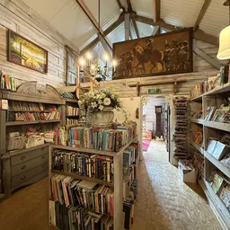 Interieur van kringloopwinkel met boekenrekken, stellingen vol tweedehands boeken, houten balken en vintage decoratie