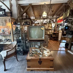 Vintage televisie en elektronica tentoongesteld in een volle kringloopwinkel met houten balkenplafond