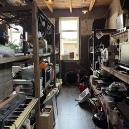Smalle winkelgang vol met elektronische apparatuur, instrumenten en diverse spullen op stellingen