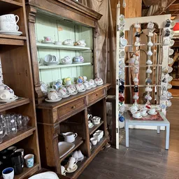 Houten vitrinekasten met uitgestalde serviesgoed, borden en aardewerk in verschillende kleuren en motieven