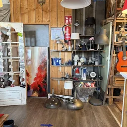 Stellingen met huishoudelijke artikelen, lampen, servies en diverse spullen in een kringloopwinkel