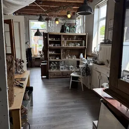 Winkelinterieur met houten vitrinekasten, hangende lampen en uitgestalde artikelen op stellingen