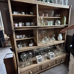 Houten vitrinekast met diverse glaswerk, vazen, kruiken en decoratieve artikelen op meerdere planken