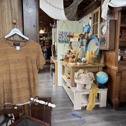 Winkelinterieur met stellingen vol huishoudelijke spullen, decoraties en gebruiksartikelen; links een bruin gestreept t-shirt