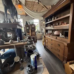 Winkelvloer met houten meubels, serviesgoed en decoratieartikelen in kringloopwinkel