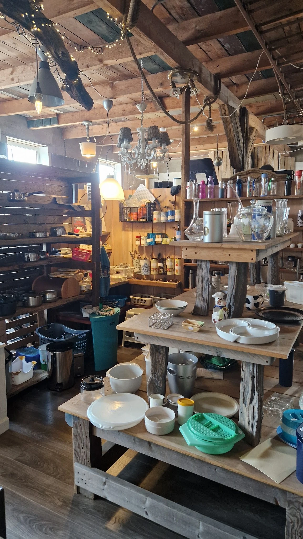 Winkelbinnenruimte met houten tafels, stellingen, huishoudartikelen en diverse spullen