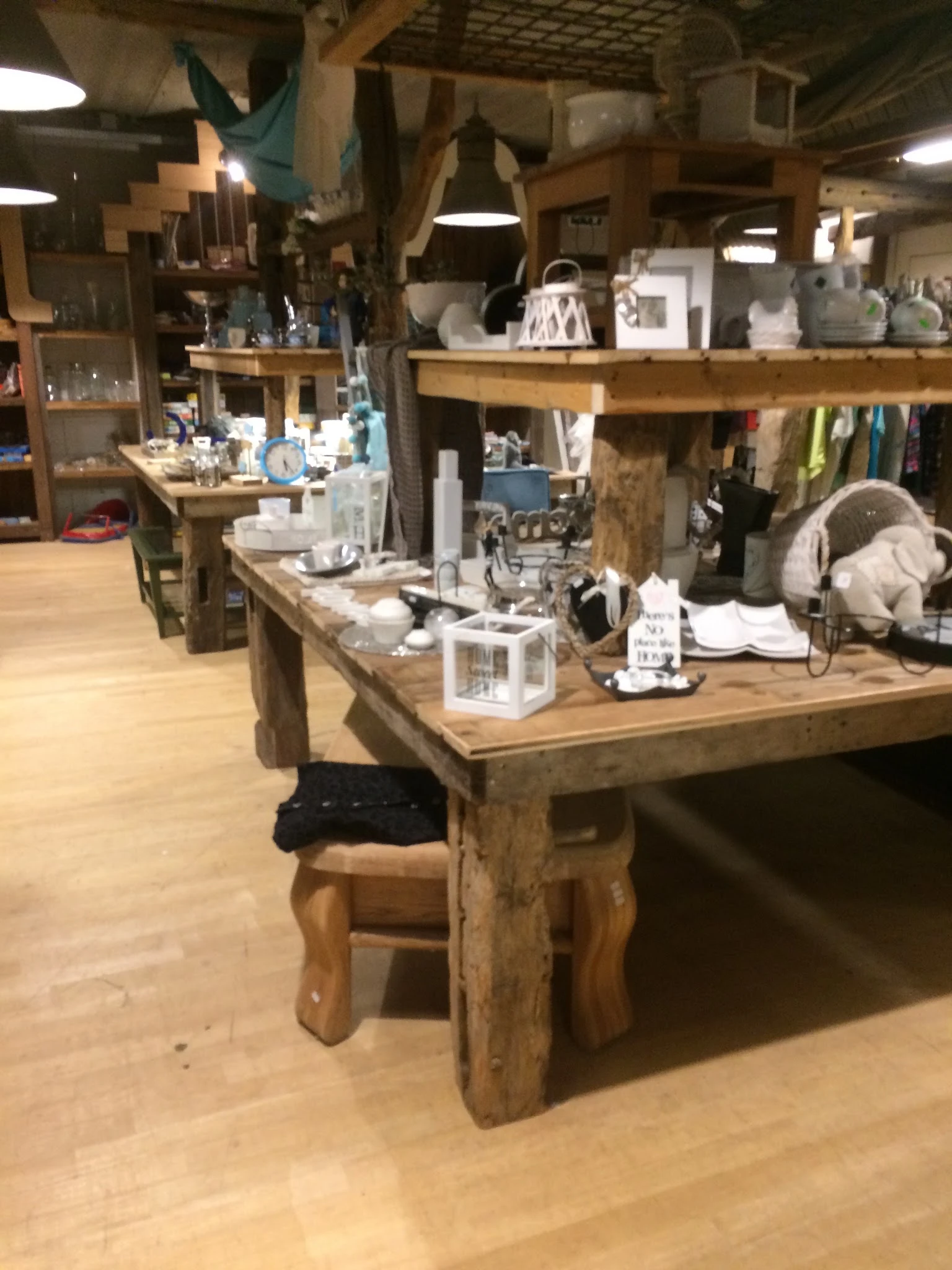 Houten werktafels met verschillende spullen en artikelen in een kringloopwinkel