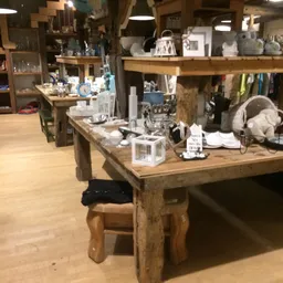 Houten werktafels met verschillende spullen en artikelen in een kringloopwinkel