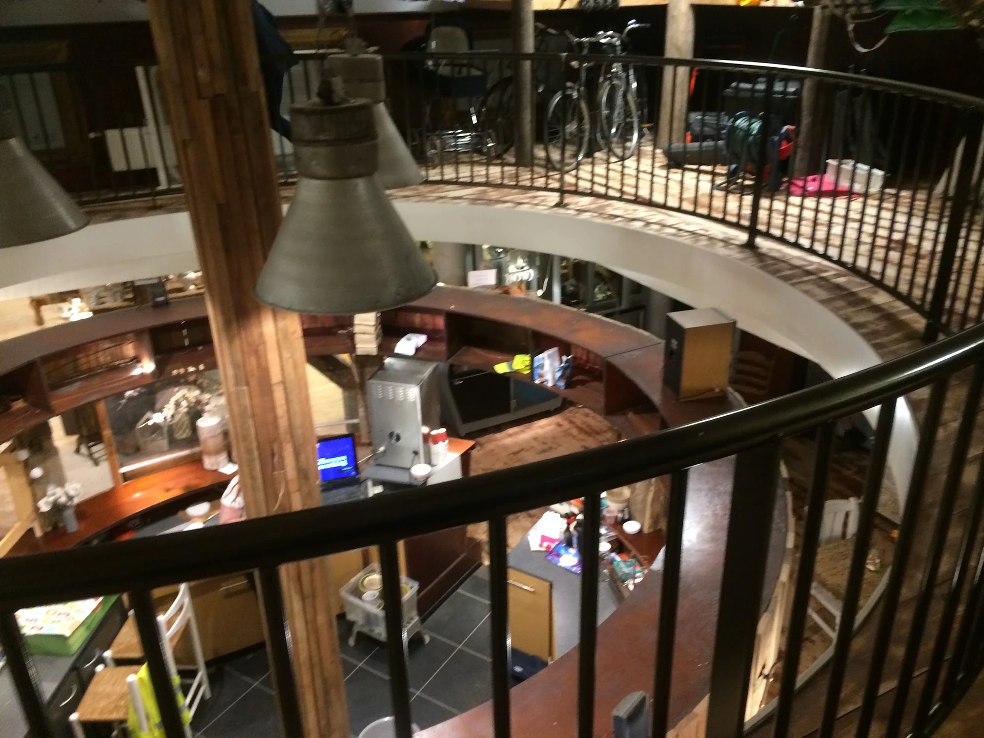 Overzicht van meerdere verdiepingen in de kringloopwinkel met stellingen, spullen en een hanglamp