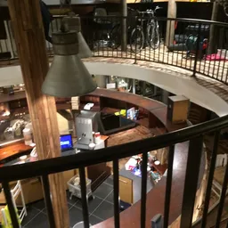 Overzicht van meerdere verdiepingen in de kringloopwinkel met stellingen, spullen en een hanglamp