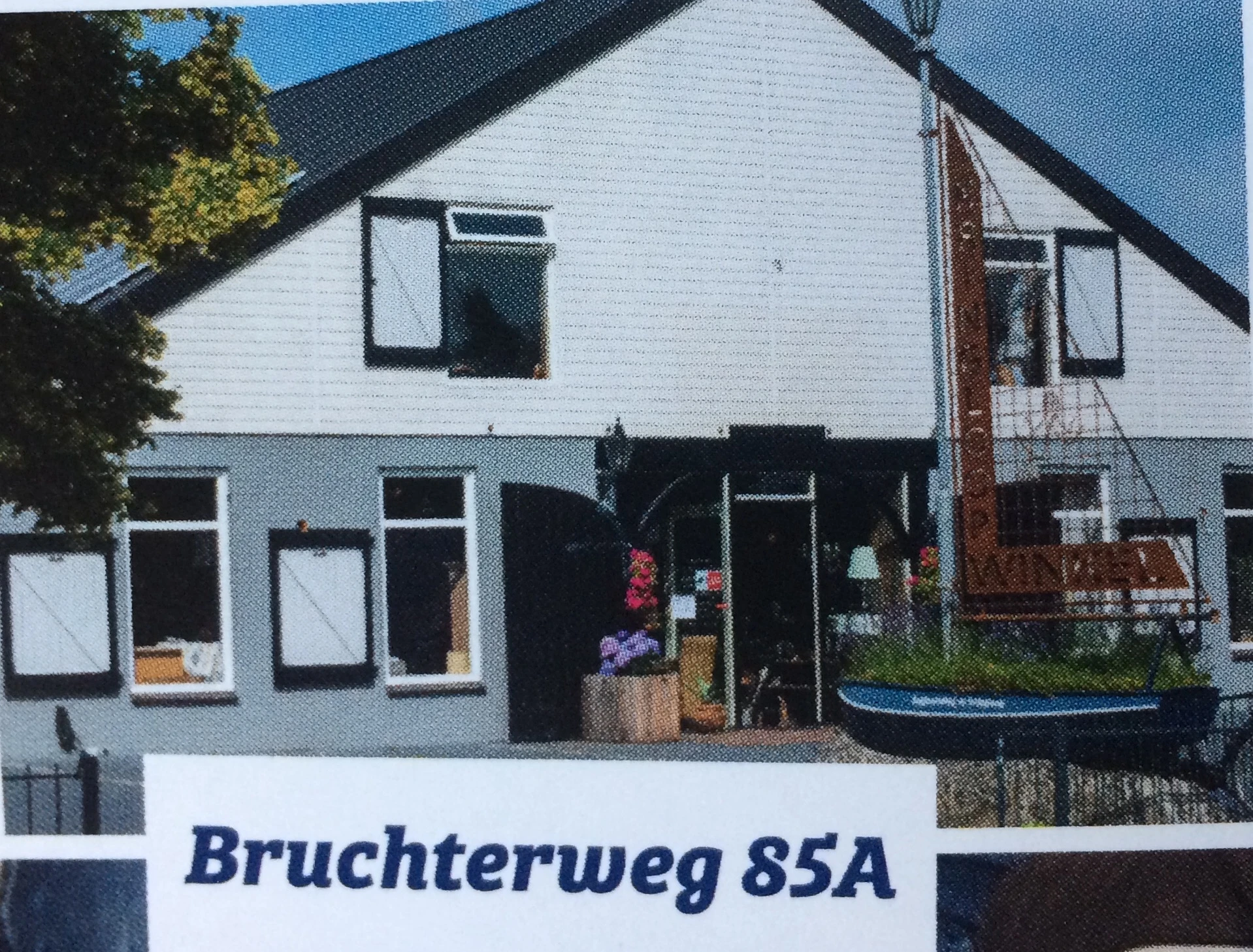 Witte kringloopwinkel met zwarte pui en ramen, adres Bruchterweg 85A zichtbaar op bord