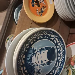 Blauw-wit servies met cartoonafbeelding, gestapeld op houten tafel