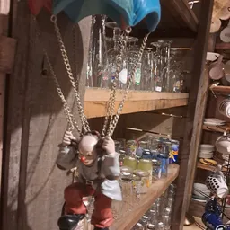 Kastje met glazen en serviesgoed, waaronder hangende kettingen met witte parels
