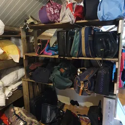 Houten stellingen met tassen, rugzakken en reisgoederen in verschillende kleuren
