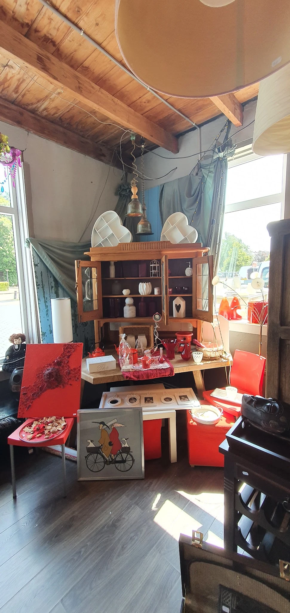 Vintage houten vitrinekast met deuren en glas, uitgestald met decoratieve items en rode accessoires